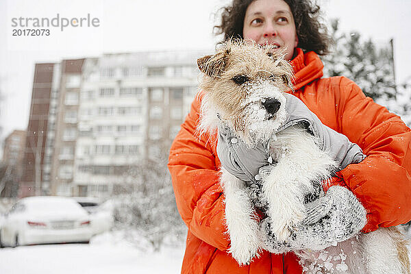 Frau hält Hund auf verschneiter Straße