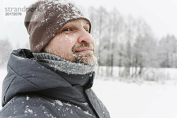 Reifer Mann mit Strickmütze auf Schneefeld