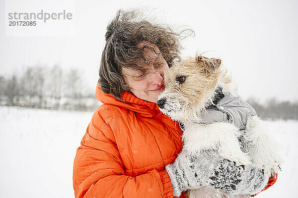 Lächelnde reife Frau mit Hund auf Schneefeld