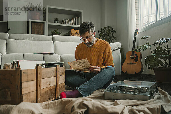 Mann liest Zeitung und sitzt zu Hause am Plattenspieler