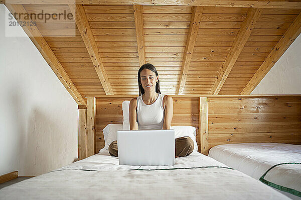 Freiberufler sitzt im Bett und benutzt Laptop im Heimbüro