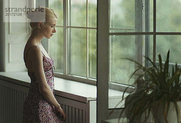 Thoughtful woman standing near window