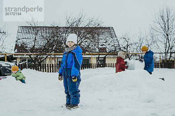 Kinder tragen warme Kleidung und spielen im Schnee