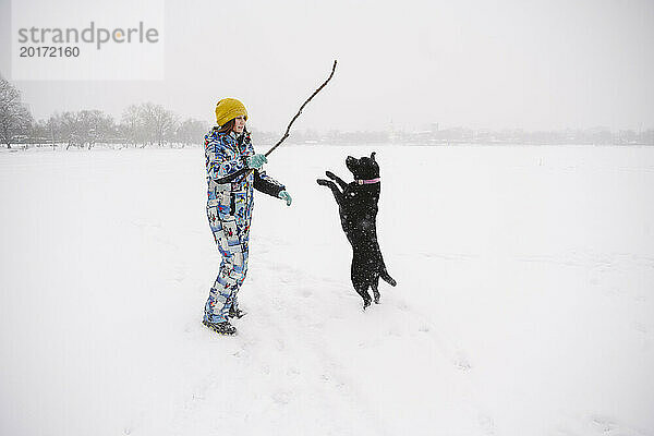 Mädchen spielt mit Hund auf Schneefeld