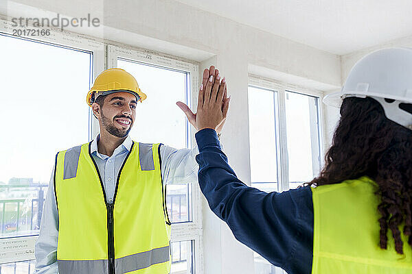 Architect giving high five to colleague at site