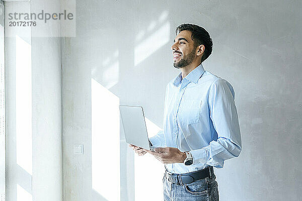 Lächelnder Architekt steht mit Laptop vor Ort