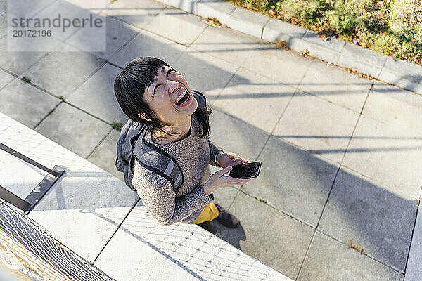 Cheerful mature woman walking with smart phone