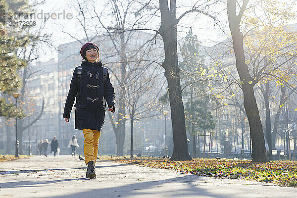 Glückliche Frau  die auf dem Fußweg im Park spaziert