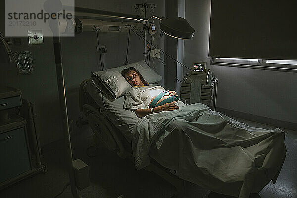 Schwangere Frau schläft auf Bett neben Geräten im Kreißsaal im Krankenhaus