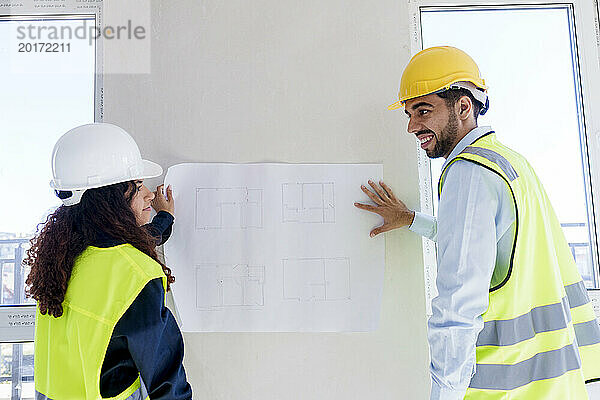 Architekten diskutieren vor Ort über den Bauplan an der Wand