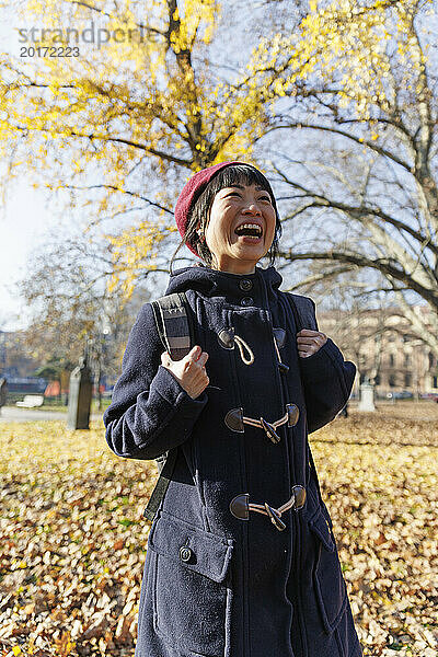 Cheerful mature woman in autumn park on sunny day