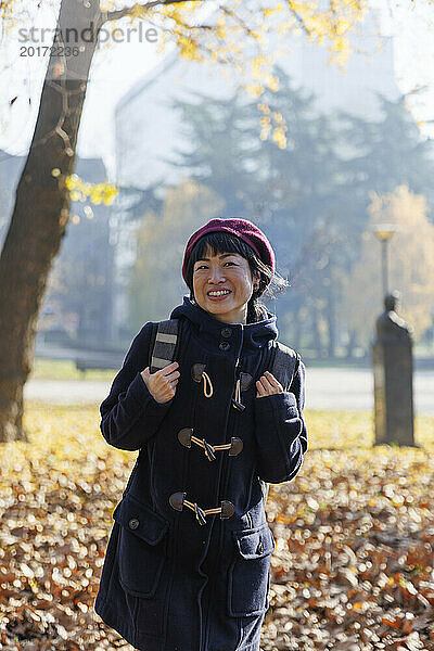 Glückliche Frau mit Rucksack im Herbstpark