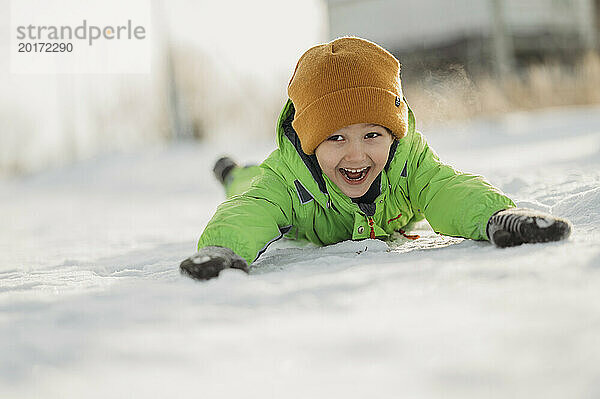 Fröhlicher Junge liegt auf Schnee