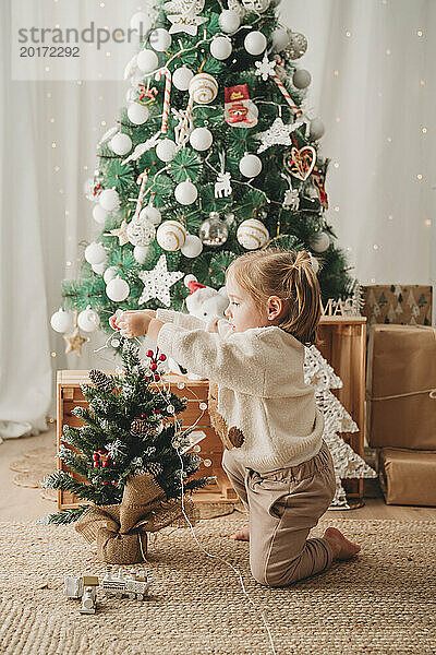 Mädchen schmückt zu Hause kleinen Weihnachtsbaum