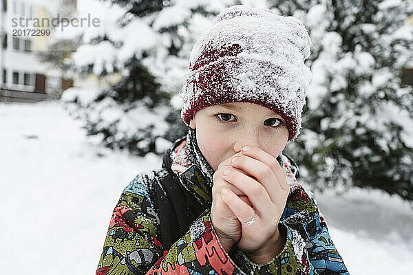 Junge bläst im Winter auf kalte Hände