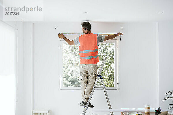 Reifer Handwerker misst Fenster in renoviertem Haus