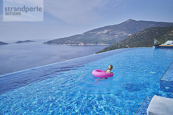 Mädchen schwimmt im blauen Pool der Villa