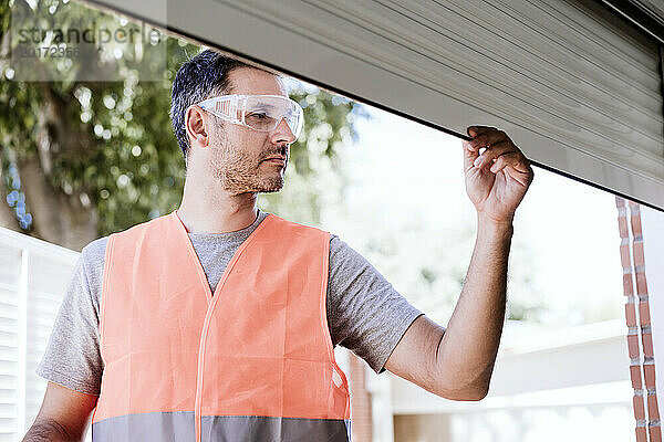 Handwerker untersucht Fensterladen an Haus  das gerade renoviert wird
