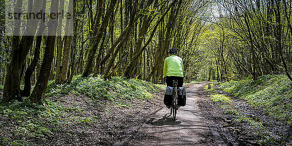 Älterer Mann radelt auf unbefestigter Straße am Cuckoo Trail in East Sussex