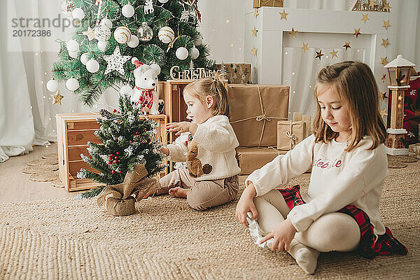 Mädchen mit Schwester schmückt zu Hause kleinen Weihnachtsbaum