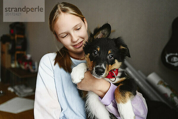 Girl holding dog in arms at home