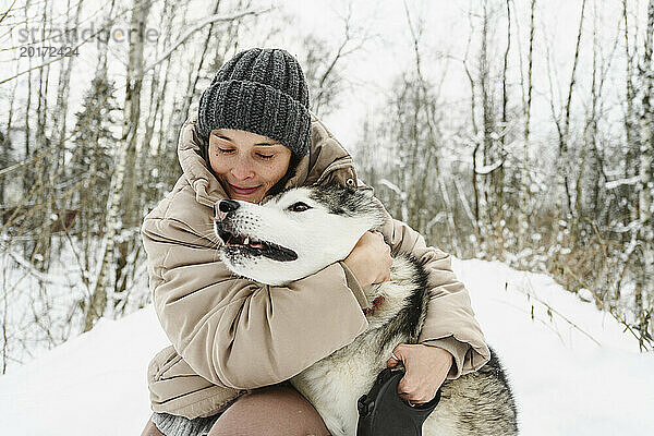 Frau umarmt Husky-Hund im Winter
