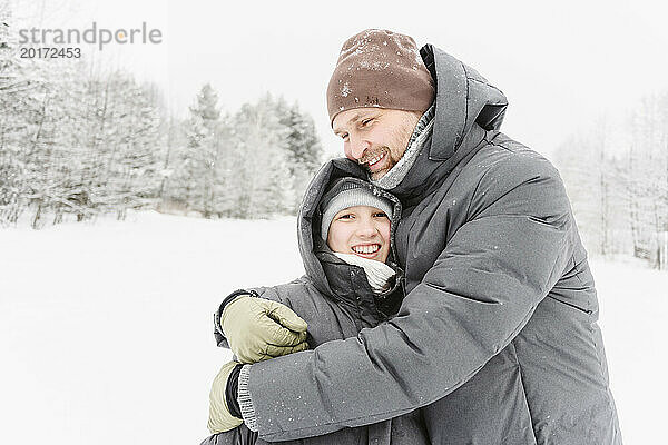 Glücklicher Mann umarmt Sohn im Winterwald