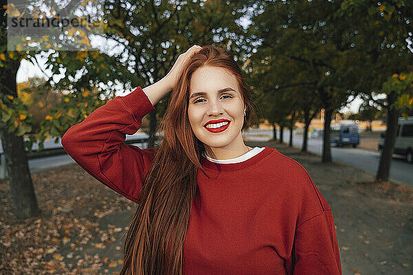 Lächelnde Frau im roten Pullover im Herbst