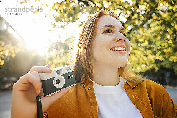 Happy woman holding camera in autumn