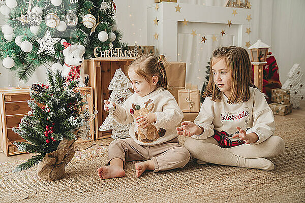 Mädchen spielen und schmücken zu Hause einen kleinen Weihnachtsbaum