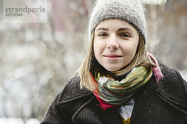 Lächelnde junge Frau mit Strickmütze im Winter