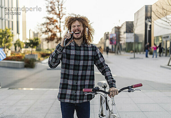 Fröhlicher Mann hält Smartphone in der Hand und hört Musik auf dem Fußweg