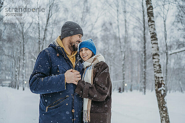 Fröhliches Paar steht im Schnee im Park