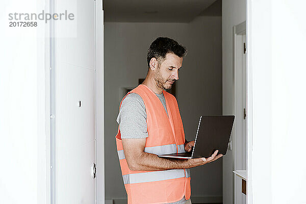 Techniker arbeitet am Laptop im renovierten Haus