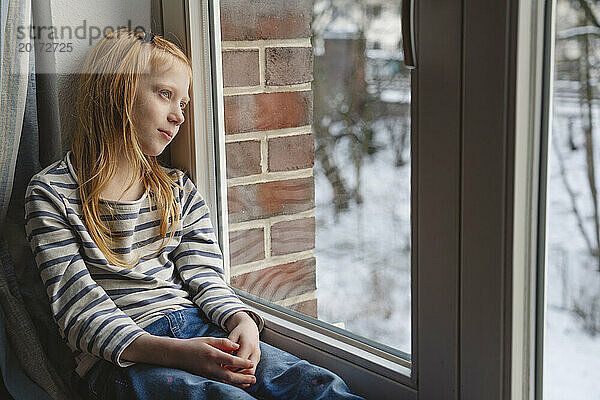 Rothaariges Mädchen schaut zu Hause aus dem Fenster