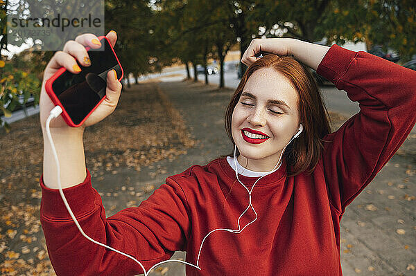 Glückliche Frau  die im Herbst mit geschlossenen Augen Musik hört