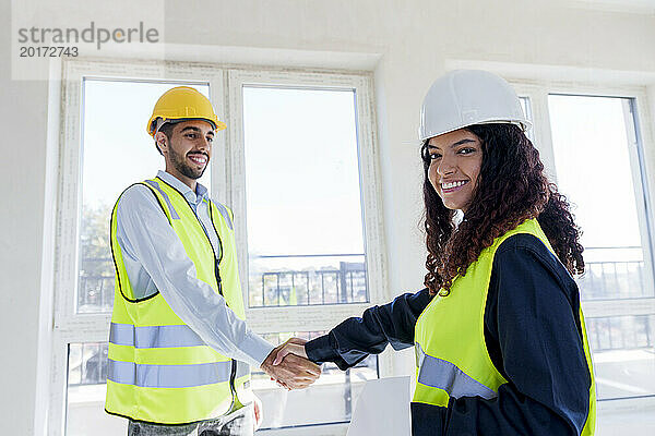 Happy engineer shaking hand with colleague at site