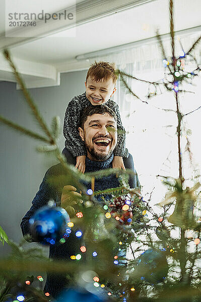 Fröhlicher Vater trägt seinen Sohn zu Hause auf den Schultern