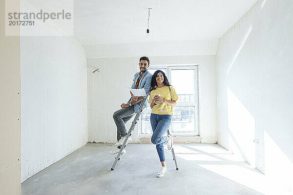 Glückliches Paar mit Bauplan im neuen Zuhause