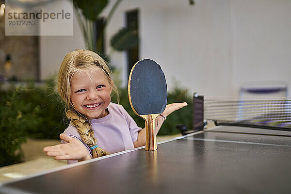 Glückliches Mädchen balanciert Tischtennisschläger in der Villa