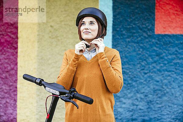 Lächelnde Frau mit Helm vor einer bunten Wand