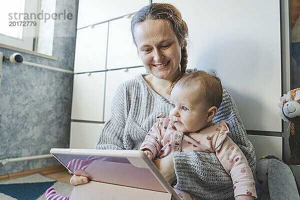 Nettes kleines Mädchen mit Mutter  die zu Hause einen Tablet-PC nutzt