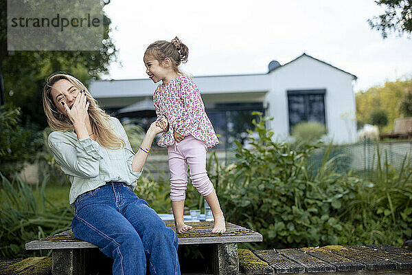 Fröhliche Mutter lacht und genießt mit ihrer Tochter am Pier