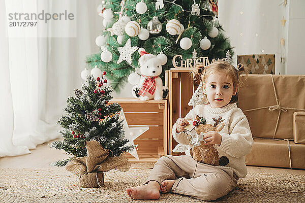 Lächelndes Mädchen  das zu Hause mit Weihnachtsdekoration spielt