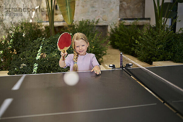 Lächelndes Mädchen  das in der Villa Tischtennis spielt