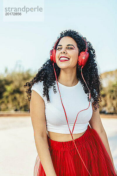 Sorglose Frau hört im Park Musik über kabelgebundene Kopfhörer