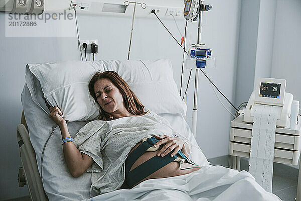Schwangere Frau mit Schmerzen im Bett im Krankenhaus