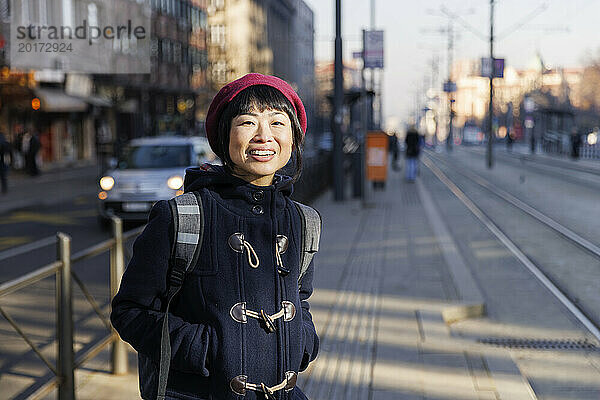 Glückliche reife Frau  die auf der Straßenbahnhaltestelle steht