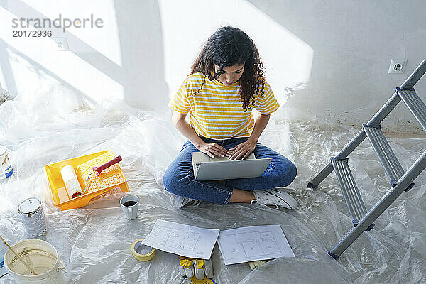 Junge Frau benutzt Laptop im renovierten Zimmer
