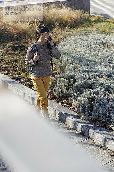Lächelnde reife Frau  die in der Nähe von Pflanzen mit dem Smartphone spricht